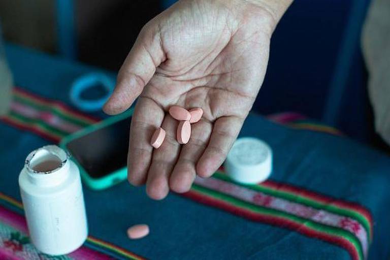 Mão de uma pessoa segurando comprimidos