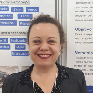 Mulher branca sorrindo, com cabelos escuros e presos e blusa preta