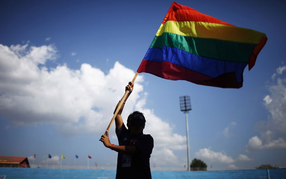 Bandeira do orgulho gay erguida por membro da comunidade LGBTQIA+ — Foto: Niranjan Shrestha/AP