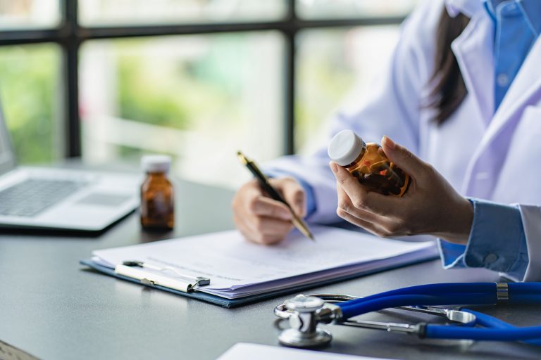 eu médico lhe escreverá uma receita e estará disponível para lhe dar instruções sobre como usá-la. Close-up de pílulas em frente a uma médica sentada em uma mesa do hospital. Médico. Prescrição médica. Médico sanitarista
