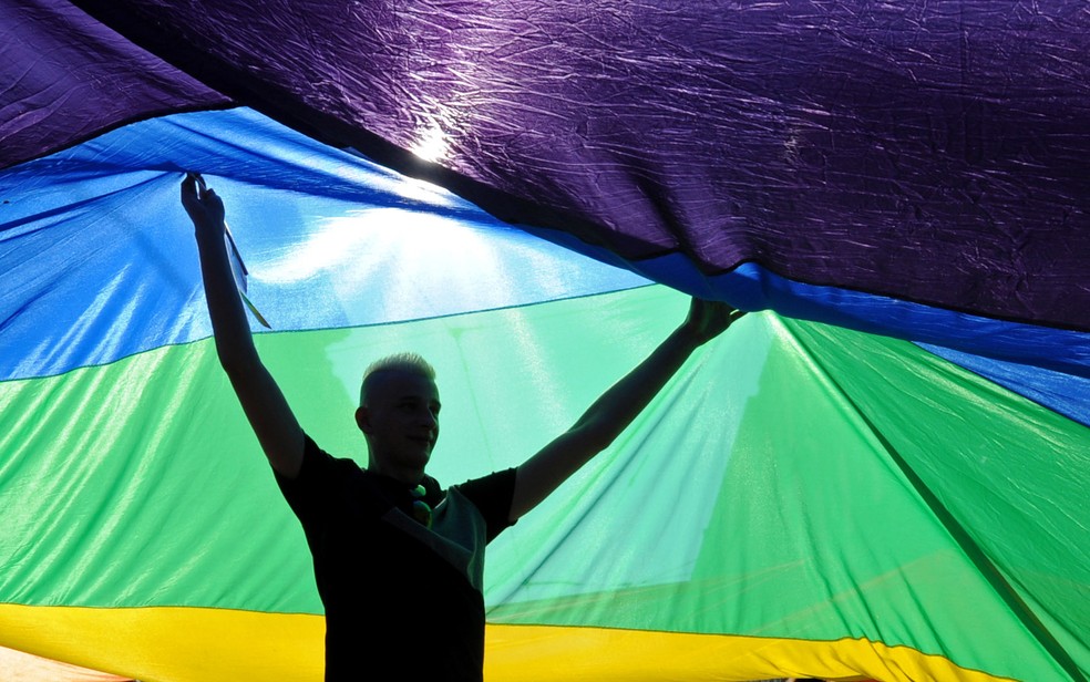 Participante ajuda a carregar uma bandeira colorida do orgulho LGBT durante marcha em Varsóvia, na Polônia — Foto: Alik Keplicz/AP